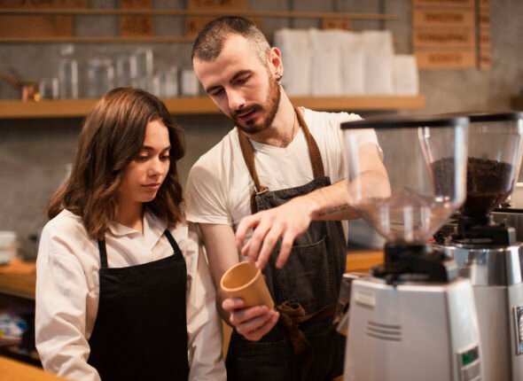 man-showing-woman-cup-with-coffee-machine